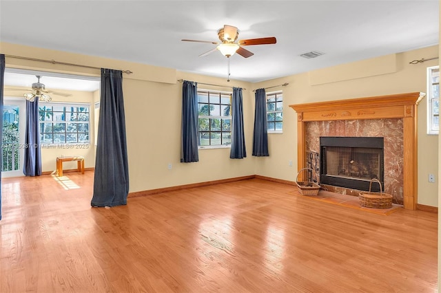 unfurnished living room with hardwood / wood-style floors, a premium fireplace, and ceiling fan