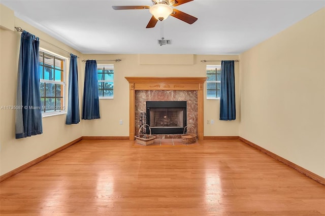 unfurnished living room with a fireplace, ceiling fan, and light wood-type flooring