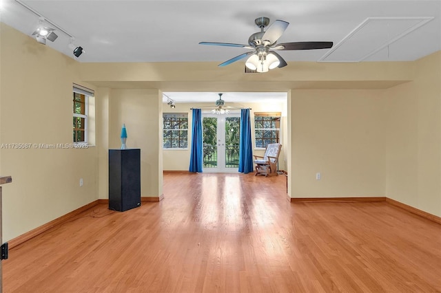 empty room with french doors, track lighting, ceiling fan, and light hardwood / wood-style flooring