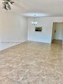 spare room with ceiling fan with notable chandelier