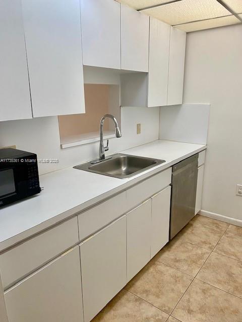 kitchen featuring white cabinetry, sink, light tile patterned floors, and stainless steel dishwasher