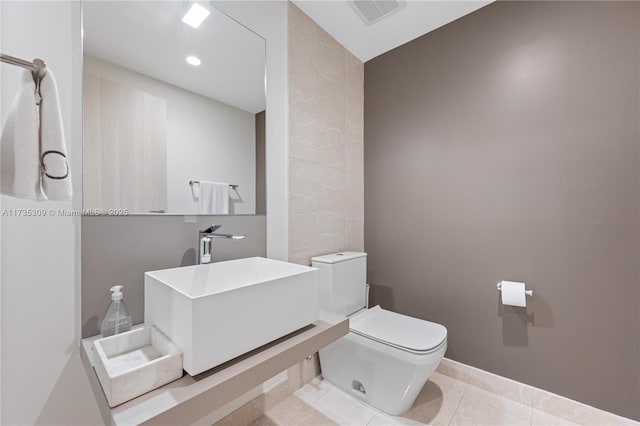 bathroom featuring tile patterned flooring, sink, tile walls, and toilet