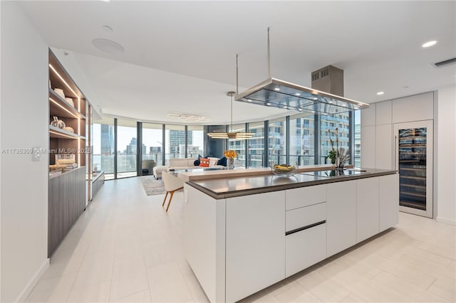 kitchen with white cabinetry, hanging light fixtures, a kitchen island, black electric cooktop, and beverage cooler