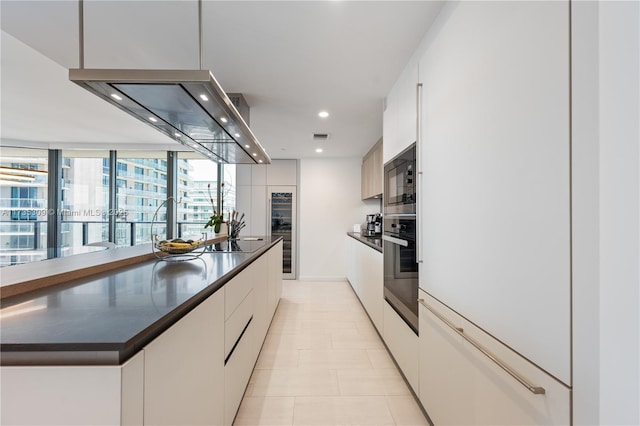 kitchen with black microwave, a spacious island, oven, and white cabinets