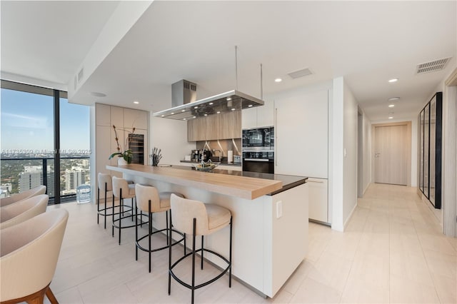 kitchen with white cabinetry, black microwave, expansive windows, and oven