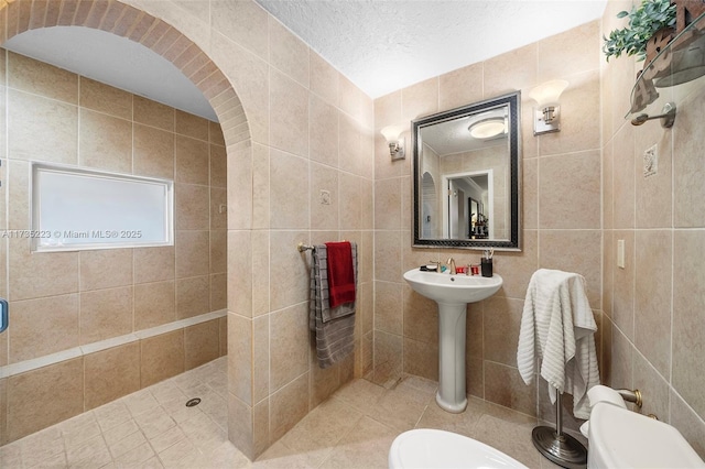 bathroom with tile walls, toilet, and tiled shower