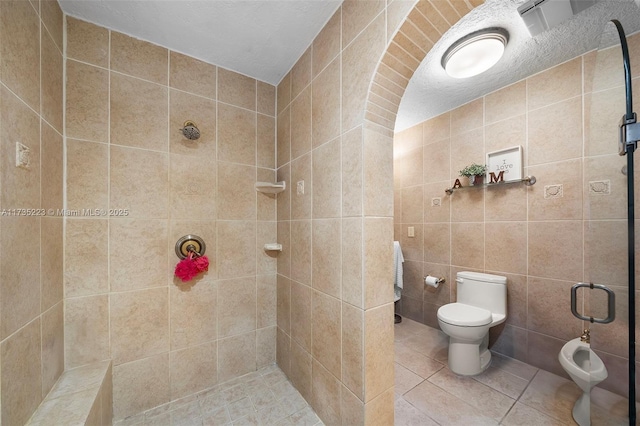 bathroom featuring walk in shower, tile patterned floors, toilet, tile walls, and a bidet