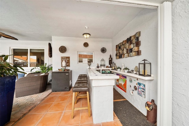 kitchen with a breakfast bar, tile patterned floors, kitchen peninsula, and a textured ceiling