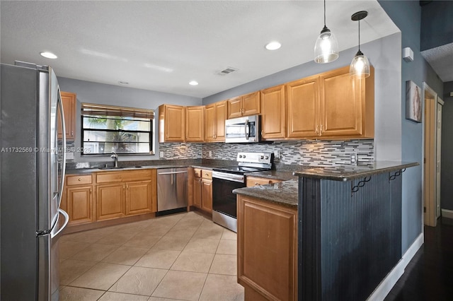 kitchen featuring appliances with stainless steel finishes, sink, backsplash, hanging light fixtures, and kitchen peninsula