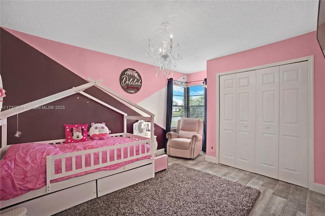 bedroom featuring a closet, hardwood / wood-style floors, a textured ceiling, and a notable chandelier