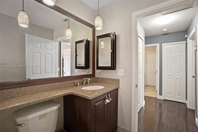 bathroom featuring vanity, toilet, hardwood / wood-style floors, and a textured ceiling