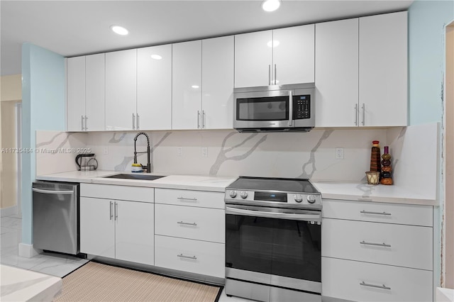 kitchen featuring sink, appliances with stainless steel finishes, light stone countertops, white cabinets, and decorative backsplash