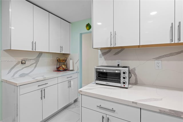 kitchen with white cabinetry and light stone counters