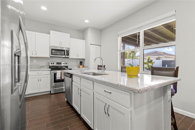 kitchen with white cabinetry, sink, stainless steel appliances, and a center island with sink