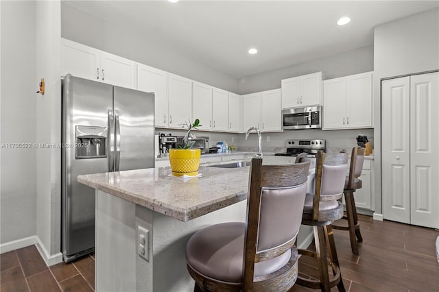 kitchen featuring white cabinetry, sink, a breakfast bar area, a kitchen island with sink, and stainless steel appliances