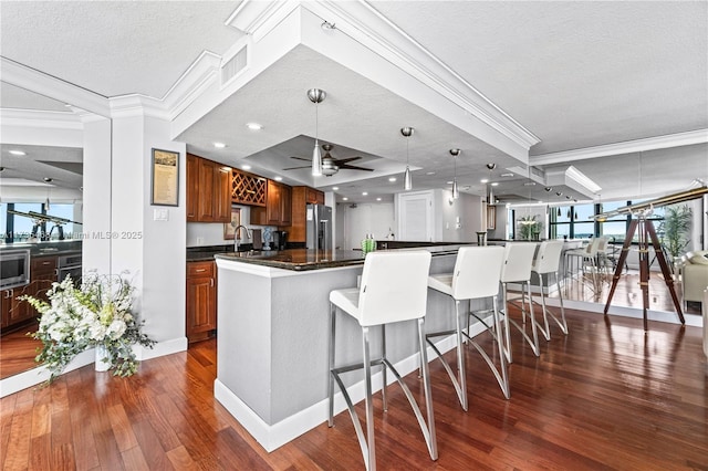 kitchen with appliances with stainless steel finishes, brown cabinetry, dark countertops, and crown molding