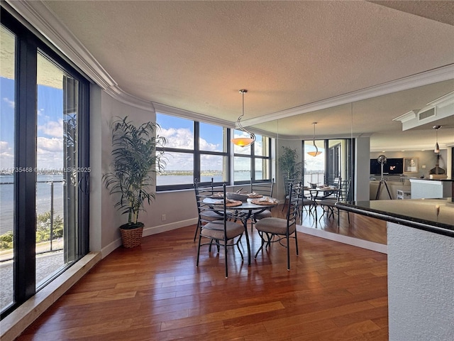 dining area with visible vents, a water view, ornamental molding, a textured ceiling, and wood finished floors