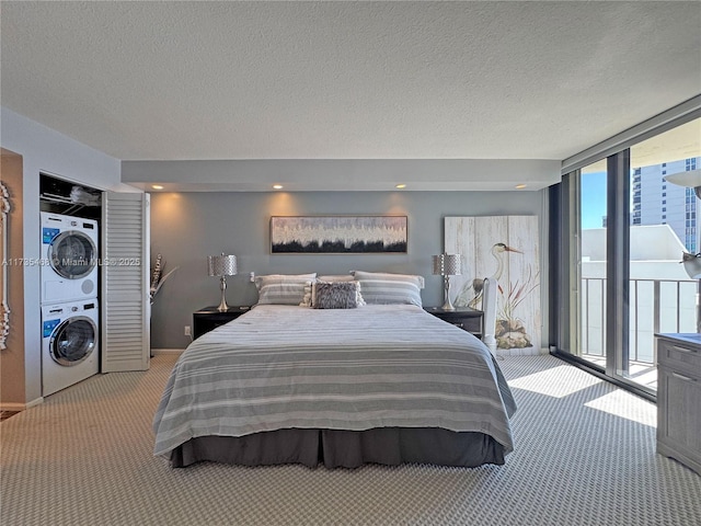 bedroom with stacked washer / dryer, light carpet, a textured ceiling, a wall of windows, and access to outside