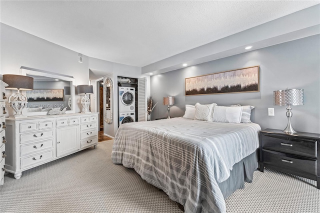 bedroom featuring carpet, a textured ceiling, stacked washer / dryer, and recessed lighting