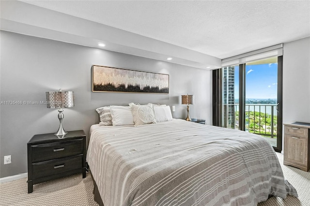 bedroom with a textured ceiling, light colored carpet, access to exterior, baseboards, and expansive windows