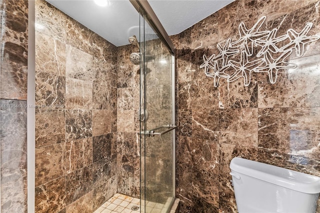 bathroom featuring a shower stall, toilet, and tile walls