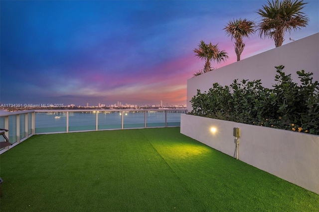 yard at dusk featuring a water view