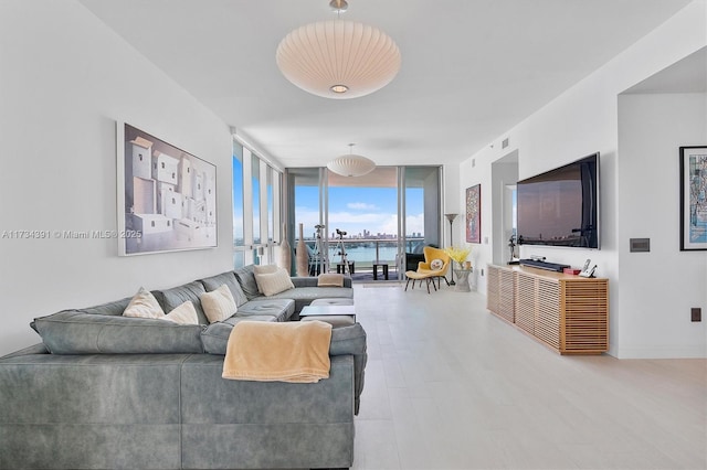 living area with expansive windows, baseboards, and wood finished floors