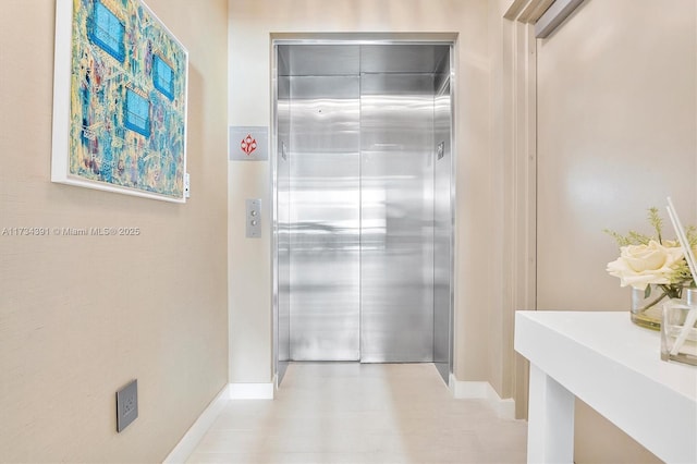 hallway featuring baseboards and elevator