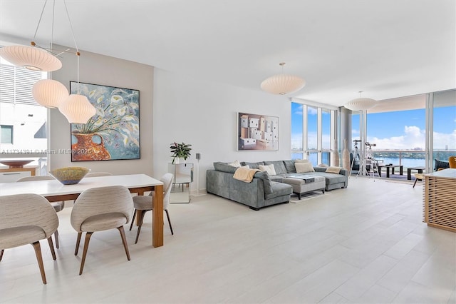 living room featuring expansive windows, a water view, and light wood-style flooring