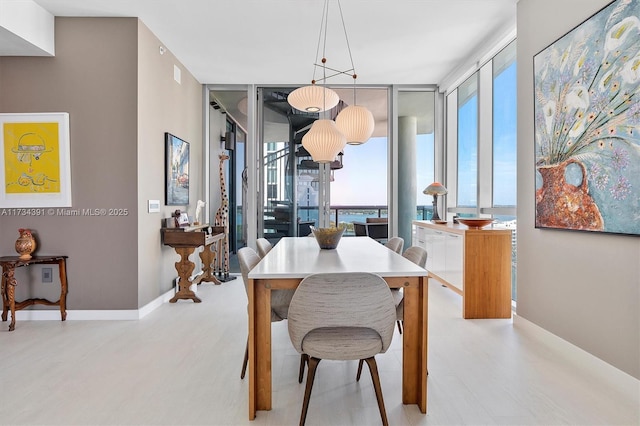 dining area with a wall of windows, baseboards, and wood finished floors