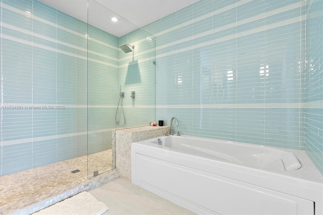 full bath featuring tile walls, a bath, and a tile shower