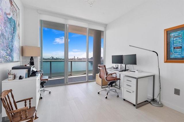 home office featuring floor to ceiling windows, baseboards, and light wood-type flooring