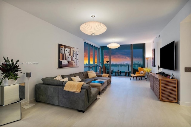 living area with a wall of windows, baseboards, and light wood-style flooring