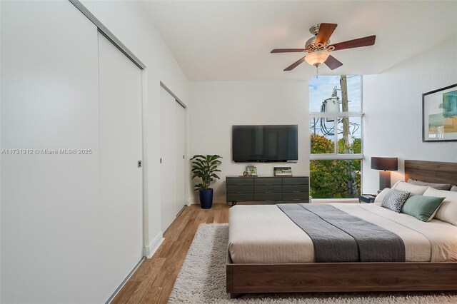 bedroom with ceiling fan, a wall of windows, and light hardwood / wood-style flooring