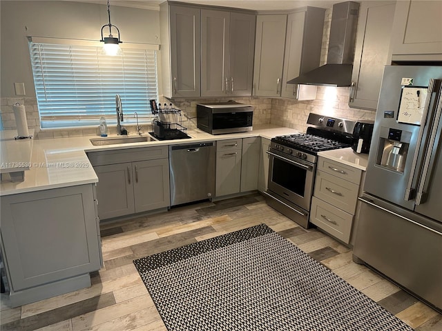 kitchen featuring gray cabinets, sink, hanging light fixtures, stainless steel appliances, and wall chimney range hood