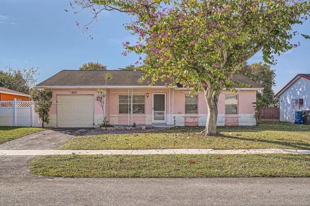 ranch-style home featuring a garage and a front lawn