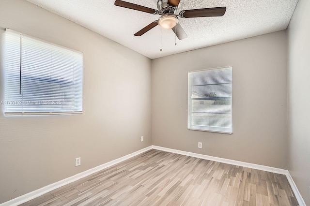 empty room with ceiling fan, light hardwood / wood-style flooring, and a textured ceiling