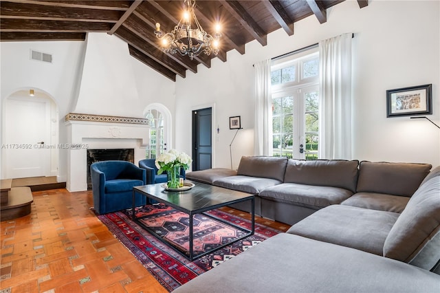 living room featuring beam ceiling, a fireplace, high vaulted ceiling, and parquet flooring