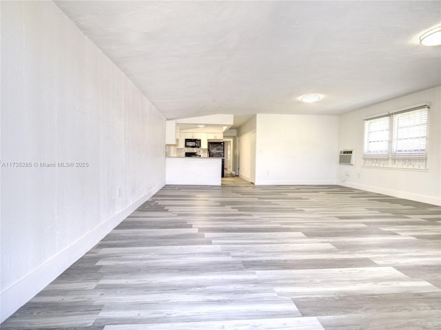 unfurnished living room with light hardwood / wood-style flooring and a wall mounted AC