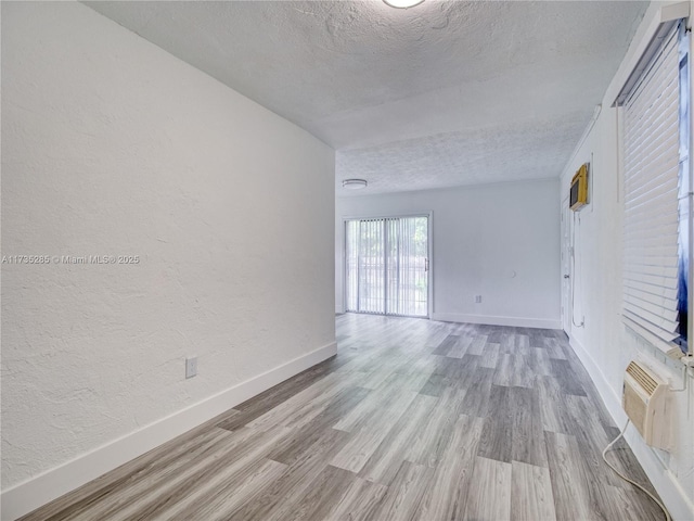 unfurnished room with a textured ceiling and light wood-type flooring