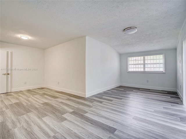 unfurnished room with a textured ceiling and light hardwood / wood-style flooring