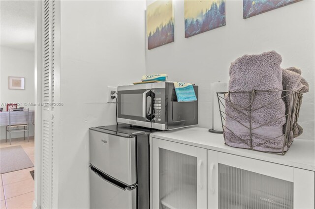 interior details with light tile patterned flooring and refrigerator