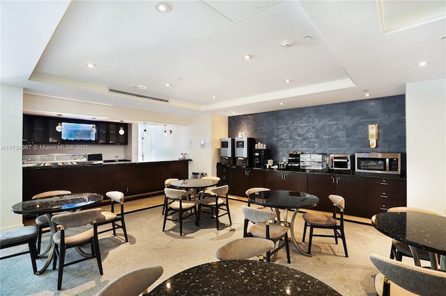 dining area featuring a tray ceiling and indoor bar