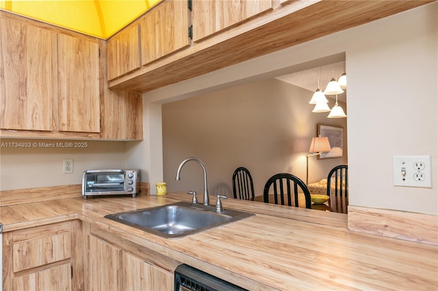 kitchen with light brown cabinetry, hanging light fixtures, wood counters, and sink