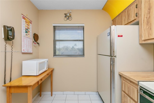 kitchen with light tile patterned floors, white appliances, and light brown cabinets