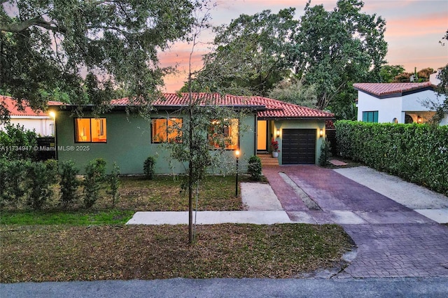 mediterranean / spanish home with driveway, stucco siding, a garage, and a tiled roof