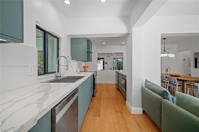 kitchen featuring a sink, light stone countertops, stainless steel appliances, light wood-style floors, and green cabinetry