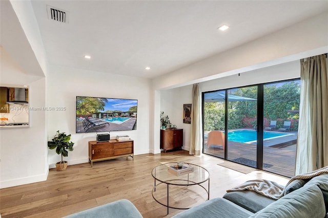 living room with baseboards, light wood-type flooring, visible vents, and recessed lighting