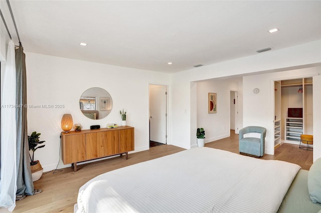 bedroom with baseboards, wood finished floors, visible vents, and recessed lighting