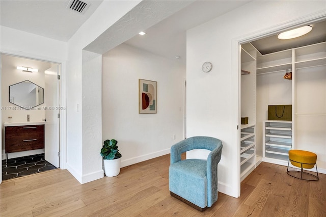 living area with visible vents, hardwood / wood-style flooring, and baseboards